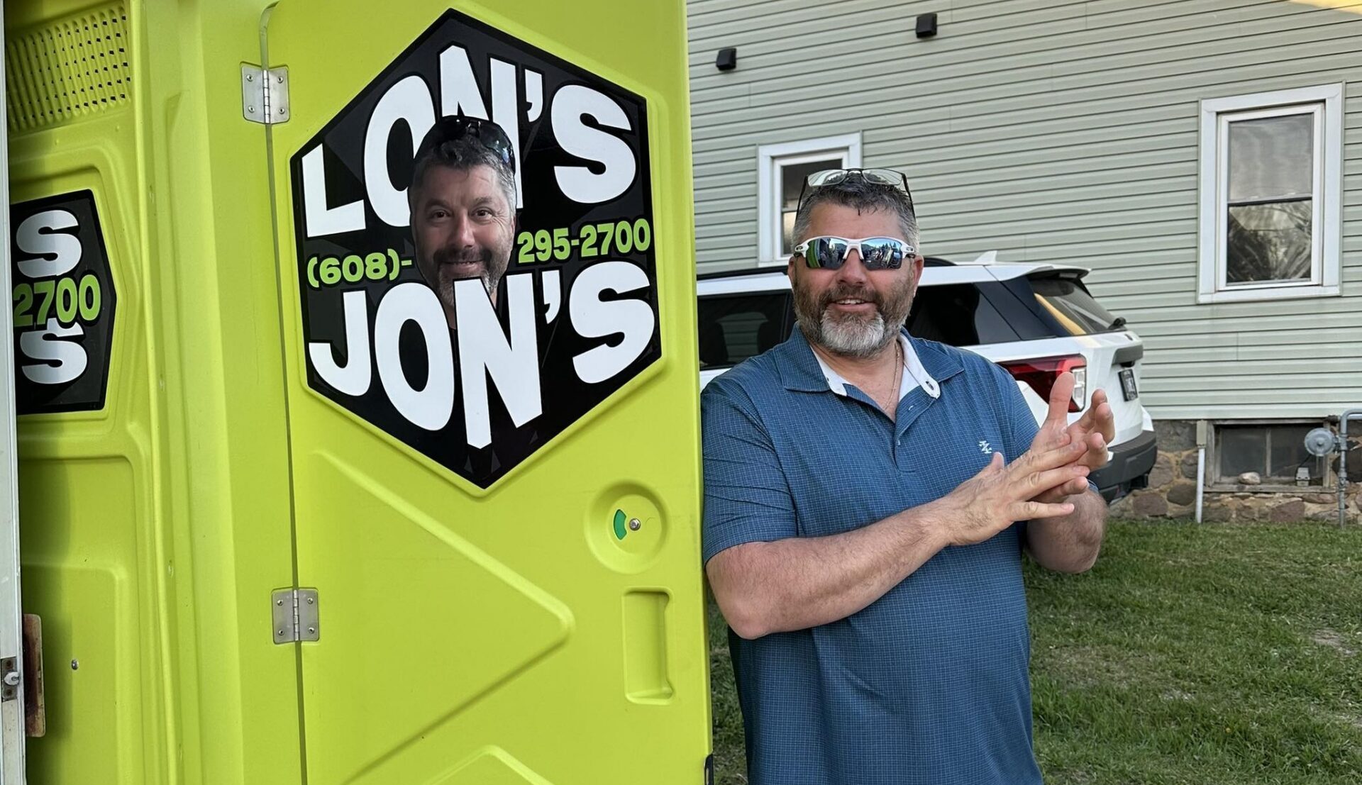 Lonny standing outside one of his porta potties